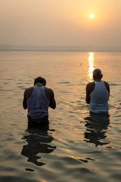 Devotees standing in holy river offering sunrise prayers during spiritual c.. Stock Photos