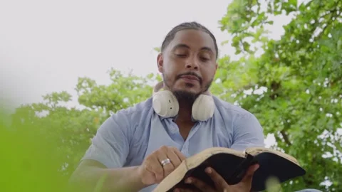 Devout african american man reading bible outdoors Видео 347557773