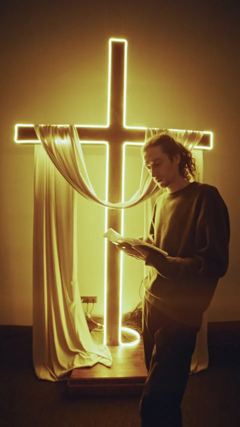 Devout Christian Praying with Bible Before Glowing Cross Stock Footage 327207408