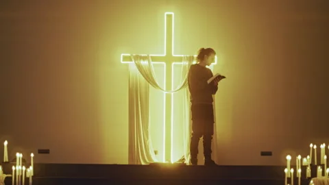 Devout Christian Praying with Bible Before Glowing Cross Stock Footage 327207514