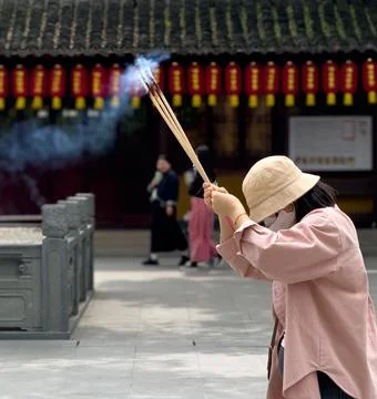 A Devout Individual Offering Incense Within a Beautiful Traditional Temple Stock Photos