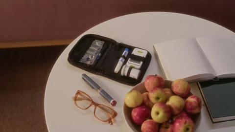 Diabetes Testing Kit on Table next to Eyeglasses and Bowl of Apples Stock Footage 320968502