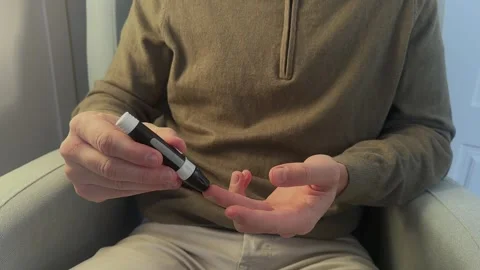 Diabetic man using lancing device for blood glucose test Stock Footage 324811747