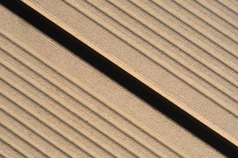 Diagonal close up of grooved composite decking board with dark gap Stock Photos