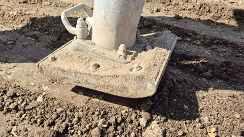 Diagonal close-up of a jumping jack rammer compacting soil on a site Stock Footage 333329074