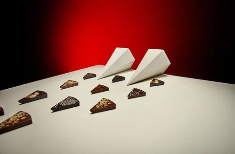 Diagonal layout of chocolate bars with white prism shapes and red backdrop Stock Photos