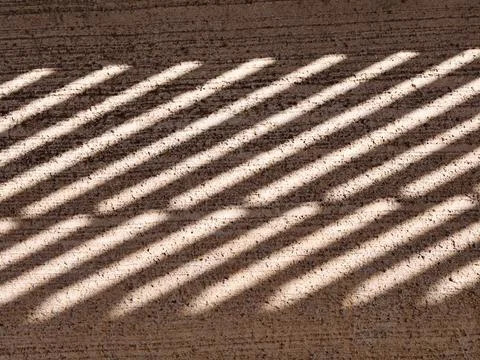Diagonal light stripes creating abstract shadow pattern on textured ground Foto stock