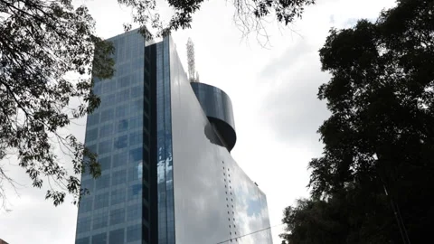 Diagonal low-angle shot of Mexico City's World Trade Center framed by trees. Video stock 158779141