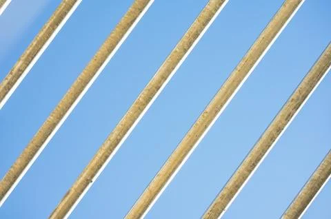 Diagonal metal bars pattern against bright clear blue sky background. Stock Photos