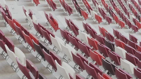 Diagonal panning shot of empty red and white seats in a large stadium or arena Stock-Footage 342402579