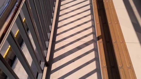 Diagonal rail shadow patterns cast on a pedestrian bridge floor Video stock 328339029