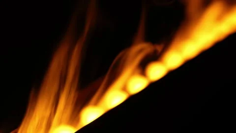 Diagonal row of golden flames flicker in pitch black evening scene Stock Footage 331956664