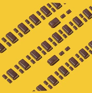 Diagonal rows of assorted chocolate bars on bold yellow surface 写真素材