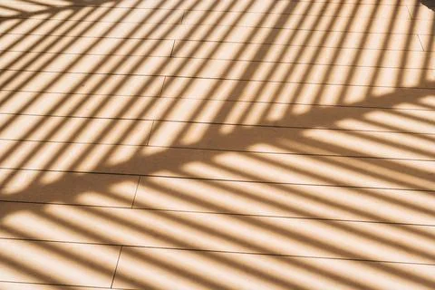 Diagonal shadow pattern on wood floor from slatted sunshade roof Stock Photos
