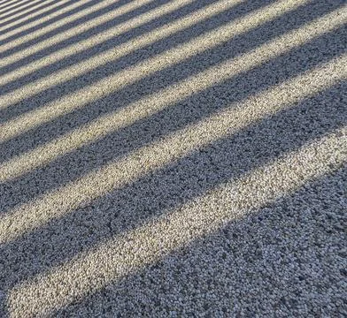 Diagonal shadow stripes creating abstract patterns on pebbles 스톡 사진