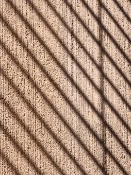 Diagonal shadows casting pattern on textured wall Fotos de archivo
