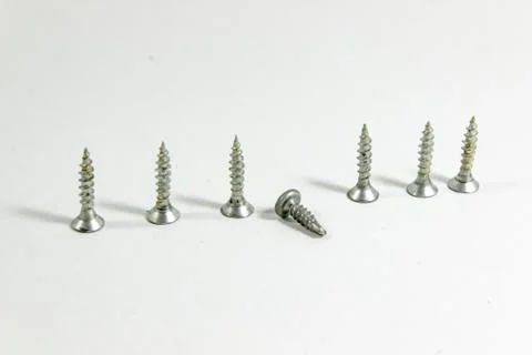 Diagonal shoot of multiple screws on white blurry background Stock Photos