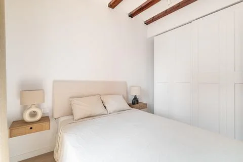 Diagonal shot a large double bed with light linen stylish bedside tables and Stock Photos