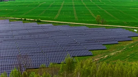 Diagonal solar panel array meets bright green crop field - aerial view of vast Stock Footage 336780767