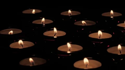 Diagonal tracking out shot of flickering tealight candle flames Stock Footage 73954905