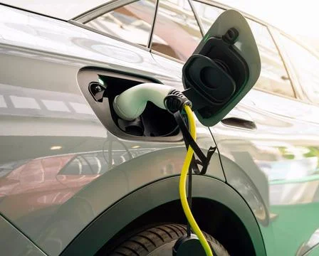 Diagonal view of EV charging plug inserted into electric car Stock Photos