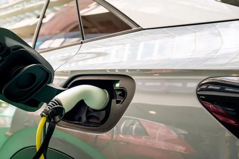 Diagonal view of EV charging plug inserted into electric car Stock Photos