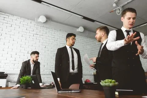 Dialogue of two men at work, young businessmen in suits working and Stock Photos