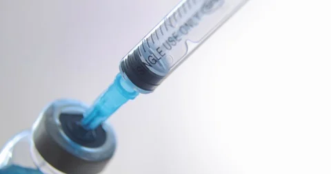Dials blue coronavirus, sars, flu vaccine into syringe on light background. Stock Footage 127709179