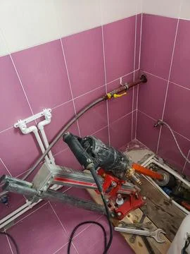 A diamond drill on an installation fixed to the wall drills with water supply a Stock Photos