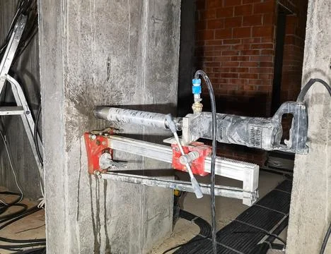 A diamond drill on a wall-mounted machine drills a hole in the concrete for an Stock Photos