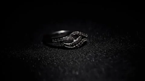 Diamond-encrusted ring with intricate design on a dark textured surface Stock Footage 317415191
