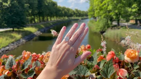 Diamond engagement ring on hand by river with flowers vertical format. Video stock 315283600