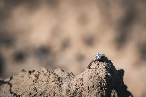 Diamond engagement ring resting on top of a rock Stock Photos