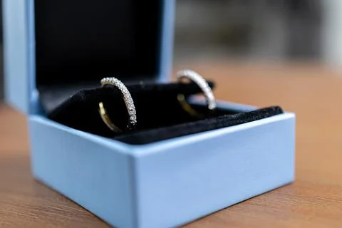 Diamond hoop earrings sit inside an elegant light blue gift box on a desk, Stock Photos