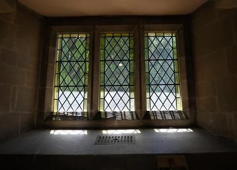 Diamond Pattern Church Windows Set in Stone Wall with Green Foliage Outside Stock Photos