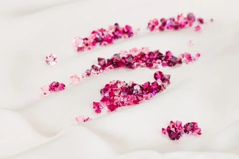 Diamond (ruby) stones heap over cream silk cloth background Foto stock
