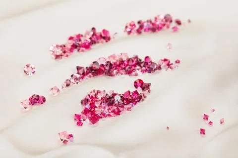 Diamond (ruby) stones heap over cream silk cloth background Stock Photos