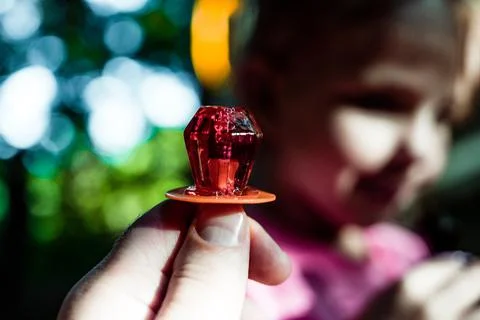 Diamond shaped ring sucker candy being held up with a child defocused in the Stock-Fotos