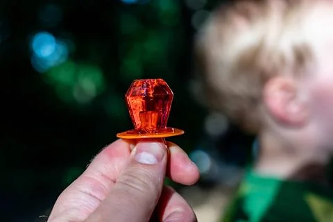 Diamond shaped ring sucker candy being held up with a child defocused in t... Stock-Fotos