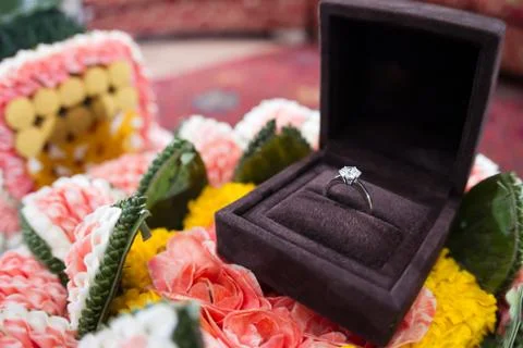 A diamond wedding ring in an open box on traditional thai style garland 스톡 사진