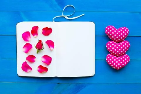 Diary notebook with rose and valentine's hearts on blue wooden background. Stock Photos