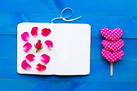 Diary notebook with rose and valentine's hearts on blue wooden background. Stock Photos