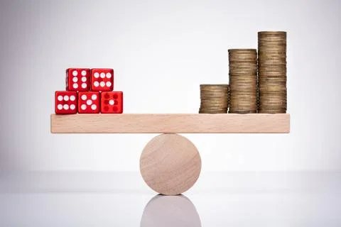Dice And Stack Of Coins On Seesaw Stock Photos