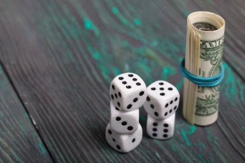 Dice are white. Near dollars rolled up in a tube. On brushed pine boards. Stock Photos