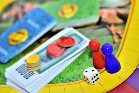 Dice, blue, red figures, chips and game money on the board. Stock Photos