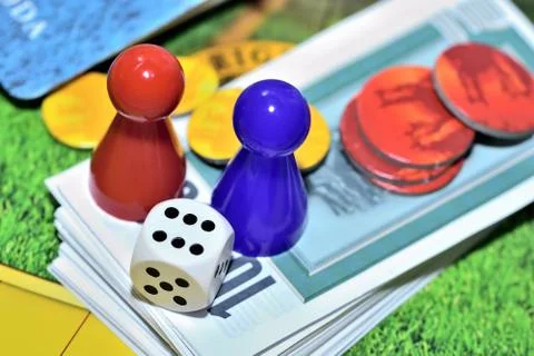 Dice, blue, red figures, chips and game money on the board. Stock Photos