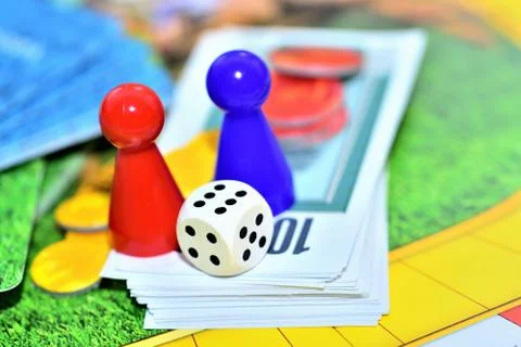 Dice, blue, red figures, chips and game money on the board. Stock Photos