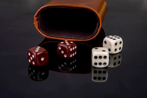 Dice with dice cup on black background Stock Photos