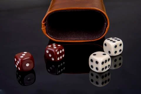 Dice with dice cup on black background Stock Photos