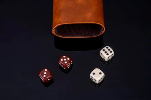 Dice with dice cup on black background Stock Photos